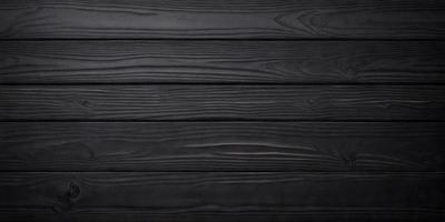 The primary subject of the image is a wooden wall with a black background. The setting is a room with a black wall, and the visual style is a black and white photo. The colors and mood of the image are predominantly dark and moody, creating a dramatic atmosphere.