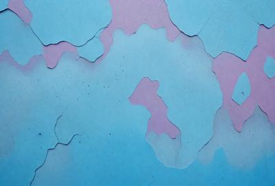 The primary subject of the image is a blue and purple wall with a pattern of peeling paint. The setting is a room with a blue background. The visual style is a close-up of the wall, showcasing the peeling paint. The dominant colors are blue and purple, creating a moody atmosphere.