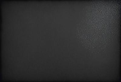 The primary subject of the image is a black background with a white light source. The setting is a dark room, and the visual style is a black and white photo. The colors and mood of the image are predominantly dark and moody, with the white light source creating a stark contrast against the black background.
