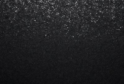 The primary subject of the image is a black background with a pattern of glittering silver stars. The setting is a dark room, and the visual style is a combination of a photo and digital art. The colors and mood of the image are predominantly dark, with the silver stars adding a touch of brightness and contrast.