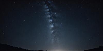 The primary subject of the image is a beautiful night sky filled with stars. The setting is a dark, nighttime environment, with the sky serving as the backdrop. The visual style of the image is a photo, capturing the stunning view of the night sky. The colors and mood of the image are predominantly dark, with the stars and the night sky creating a serene and peaceful atmosphere.