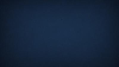 The primary subject of the image is a dark blue sky with no clouds. The setting is a vast, open space with no visible landmarks or objects. The visual style is a black and white photo, which adds a sense of timelessness and simplicity to the scene. The colors and mood are predominantly dark and moody, with the blue sky serving as the main focal point.