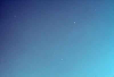 The primary subject of the image is the night sky, which is filled with stars. The setting is a clear, dark blue sky, with no clouds or other obstructions visible. The visual style of the image is a photo, capturing the beauty of the night sky. The colors and mood of the image are predominantly dark and serene, with the stars and the vast expanse of the sky creating a sense of tranquility and wonder.