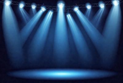 The primary subject of the image is a stage with a blue light shining on it. The setting is a darkened stage, and the visual style is a photo. The dominant colors are blue and black, creating a moody atmosphere.