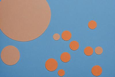 The primary subject of the image is a collection of orange circles, which are placed on a blue background. The setting appears to be a creative workspace, possibly a classroom or an art studio. The visual style of the image is a combination of digital art and illustration, as the orange circles are placed on a blue background, creating a visually appealing and engaging scene. The colors and mood of the image are vibrant and lively, with the orange circles standing out against the blue background.