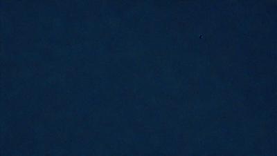 The primary subject of the image is a dark blue sky. The setting is a vast, open space with no visible landmarks or objects. The visual style is a natural, outdoor scene. The colors and mood are predominantly dark and moody, with the blue sky being the main focus of the image.