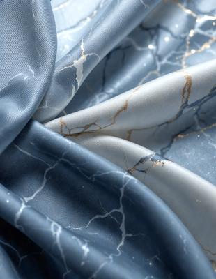 The primary subject of the image is a blue fabric with a marbled pattern. The setting is a close-up view of the fabric, showcasing its intricate design. The visual style is a realistic representation of the fabric, capturing its texture and pattern. The colors and mood of the image are predominantly blue, creating a calm and serene atmosphere.