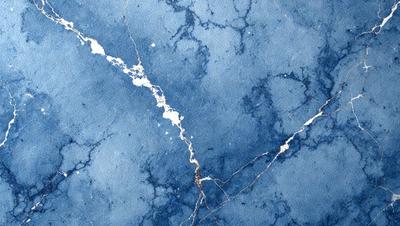 The primary subject of the image is a blue wall with a crack in it. The setting is a room with a blue surface, possibly a wall or a table. The visual style is a close-up of the cracked blue wall, which gives the image a somewhat distorted appearance. The dominant colors are blue and white, with the cracked blue wall being the main focus of the image.