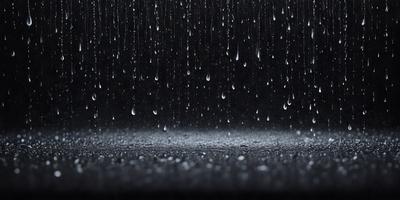 The primary subject of the image is a rainy scene with a dark background. The setting is a rainy day, and the visual style is a photo. The colors and mood of the image are dominated by the rain, with the dark background and the raindrops creating a moody atmosphere.