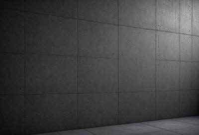 The primary subject of the image is a large, gray concrete wall. The setting is a dark room, and the visual style is a black and white photo. The dominant colors are gray and black, creating a moody atmosphere.