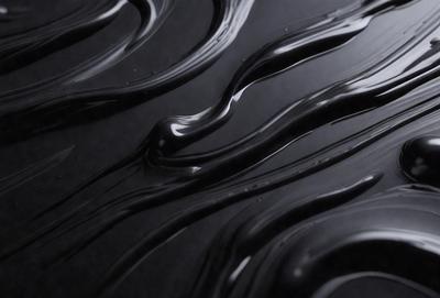 The primary subject of the image is a close-up of a black liquid, possibly chocolate or a similar substance, with a swirling pattern. The setting is a dark background, which contrasts with the liquid. The visual style appears to be a close-up of a swirling pattern, possibly a digital art or illustration. The colors are predominantly black, with the swirling pattern adding a sense of depth and movement to the image.