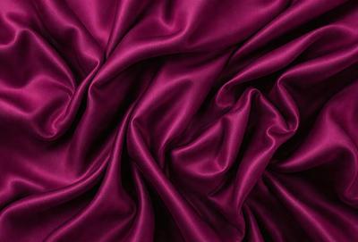 The primary subject of the image is a close-up of a purple fabric, showcasing its texture and color. The setting is a dark background, which emphasizes the purple fabric. The visual style is a close-up, focusing on the details of the fabric. The colors and mood of the image are predominantly purple, creating a sense of luxury and elegance.