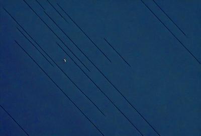 The primary subject of the image is a moon, which is seen in the sky. The setting is a dark blue sky, and the visual style appears to be a photo. The colors and mood of the image are predominantly dark and moody, with the moon being the main source of light in the scene.