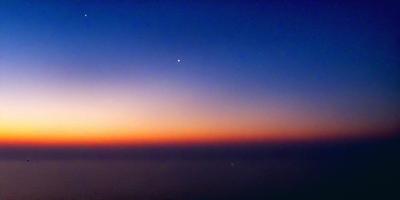 The primary subject of the image is the night sky, which is filled with stars. The setting is a vast expanse of the ocean, with the sky serving as the backdrop. The visual style of the image is a photo, capturing the beauty of the night sky and the ocean. The colors and mood of the image are serene and peaceful, with the stars and the ocean creating a sense of tranquility.