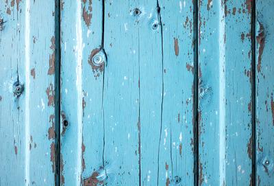 The primary subject of the image is a blue wooden wall with a weathered appearance. The setting is a room with a blue wooden wall, and the visual style is a photo. The dominant colors are blue and white, creating a calm and serene atmosphere.