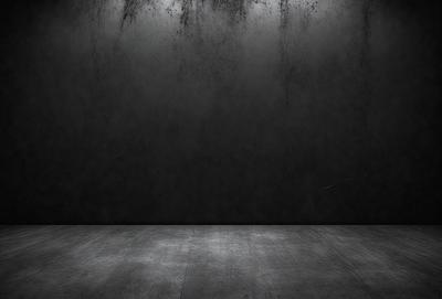 The primary subject of the image is a black wall with a gray floor. The setting is a dark room, and the visual style is a black and white photo. The colors and mood of the image are predominantly dark and moody, with the black wall and gray floor creating a sense of emptiness and mystery.