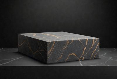The primary subject of the image is a square box made of marble. The box is placed on a black surface, which serves as the setting or background. The visual style of the image is a photo, showcasing the marble box and its texture. The colors and mood of the image are predominantly black and gray, giving it a sleek and modern appearance.