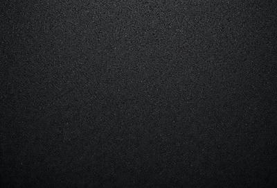 The primary subject of the image is a black background with a texture that resembles a stone wall. The setting is a dark room, and the visual style is a close-up of the black background. The colors and mood of the image are predominantly dark and moody, with the black background being the main focus.
