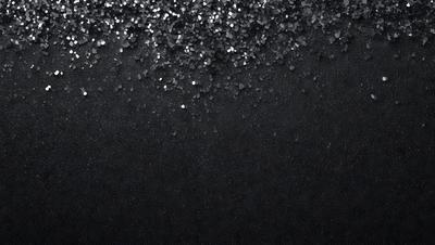 The primary subject of the image is a black background with a pattern of glittering silver stars. The setting is a dark, starry night, and the visual style is a combination of a photo and digital art. The colors and mood are predominantly dark and mysterious, with the silver stars adding a touch of brightness and intrigue to the scene.