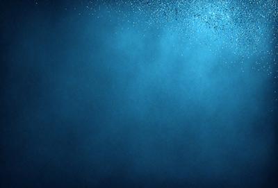 The primary subject of the image is a blue background with a few white specks. The setting is a dark blue ocean, and the visual style is a photo. The colors and mood of the image are predominantly dark and moody, with the blue background and white specks adding a touch of contrast.