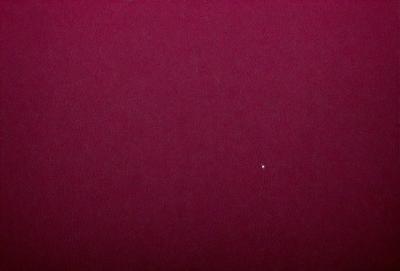 The primary subject of the image is a red background, which appears to be a wall or a surface. The setting/background is a dark, possibly purple, space. The visual style of the image is a close-up of the red background, which gives it a bold and striking appearance. The colors and mood of the image are predominantly dark and moody, with the red background standing out as the main focal point.