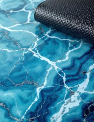 The primary subject of the image is a blue marble tabletop with a black leather case on top of it. The setting is a table with the marble surface, and the visual style appears to be a photo. The dominant colors are blue and black, creating a calm and sophisticated atmosphere.
