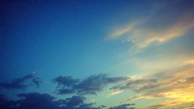 The primary subject of the image is a cloudy blue sky with a few clouds scattered throughout. The setting is a clear day with a beautiful blue sky, and the visual style is a natural, outdoor scene. The colors and mood of the image are predominantly blue and calm, creating a serene atmosphere.