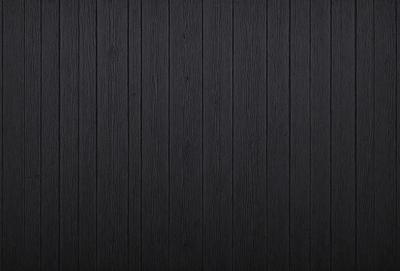 The primary subject of the image is a wooden wall. The setting is a dark room, and the visual style is a black and white photo. The colors and mood of the image are predominantly dark, creating a moody atmosphere.