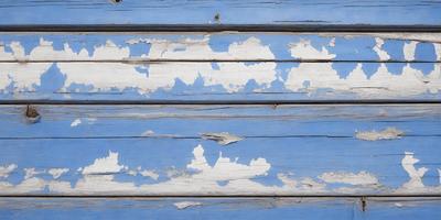 The primary subject of the image is a blue wall with peeling paint. The setting is a room with a blue wall, and the visual style is a photo. The dominant colors are blue and white, and the overall atmosphere is somewhat aged and worn.