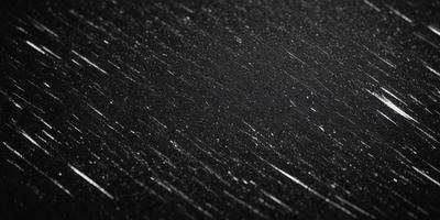 The primary subject of the image is a black background with a pattern of white streaks or stars. The setting appears to be a night sky, and the visual style is a close-up of the pattern. The colors and mood of the image are predominantly dark and moody, with the white stars contrasting against the black background.