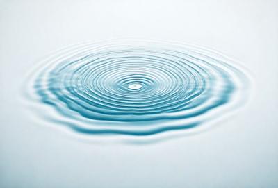 The primary subject of the image is a blue, circular wave in a body of water. The wave is surrounded by a white surface, which could be the ocean floor or a white background. The visual style of the image is a photo, capturing the natural beauty of the wave. The dominant colors in the image are blue and white, creating a serene and calming atmosphere.