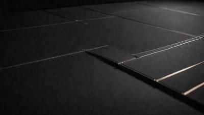 The primary subject of the image is a piece of glass, which is placed on a black surface. The setting appears to be a dark room, and the visual style is a close-up of the glass. The colors in the image are predominantly black, giving it a moody atmosphere.