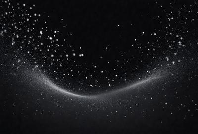 The primary subject of the image is a close-up of a cloud of smoke or dust, with a black background. The visual style appears to be a photo, as it captures the smoke or dust in a realistic manner. The colors and mood of the image are predominantly dark, with the smoke or dust being the main focus.