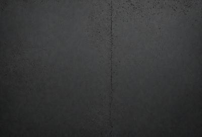 The primary subject of the image is a black wall with a gray texture. The setting is a room with a black background, and the visual style is a close-up of the wall. The colors and mood of the image are predominantly dark and moody, with the black and gray tones creating a sense of depth and contrast.