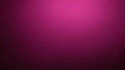 The primary subject of the image is a close-up of a pink background. The setting is a dark room, and the visual style appears to be a photo. The dominant colors in the image are pink, and the overall atmosphere is warm and inviting.
