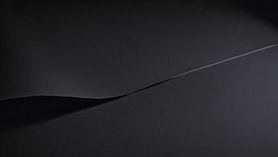The primary subject of the image is a black background with a white line or a white object on it. The setting appears to be a dark room, and the visual style is a close-up of the white line or object. The colors and mood of the image are predominantly dark and moody, with the white line or object standing out against the black background.