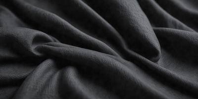 The primary subject of the image is a black fabric, which is the main object, scene, or focus of the image. The setting or background is a dark room, and the visual style is a photo. The colors and mood of the image are predominantly dark and moody, with the black fabric as the dominant color.