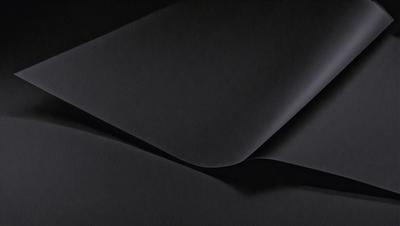 The primary subject of the image is a black cloth, which is the main object, scene, or focus of the image. The setting or background is a dark room, and the visual style is a close-up of the black cloth. The colors and mood of the image are predominantly dark and moody, with the black cloth being the dominant color.