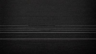 The primary subject of the image is a black and white photo of a carpeted floor. The setting is a dark room with a carpeted floor, and the visual style is a black and white photo. The colors and mood of the image are predominantly dark and moody, with the black carpet and the dark room creating a sense of depth and mystery.