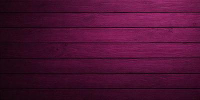 The primary subject of the image is a wooden wall with a purple color. The setting is a room with a wooden floor. The visual style is a close-up of the wooden wall, showcasing its texture and color. The dominant colors are purple and brown, creating a warm and cozy atmosphere.