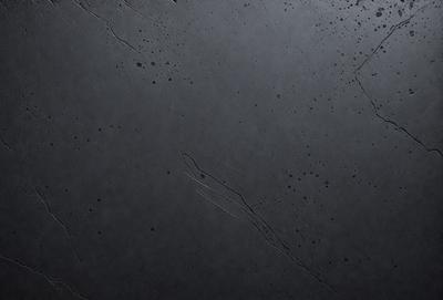 The primary subject of the image is a black surface with a few white spots. The setting is a black background, and the visual style appears to be a close-up of the black surface. The colors and mood of the image are predominantly dark, with the white spots adding a touch of contrast.