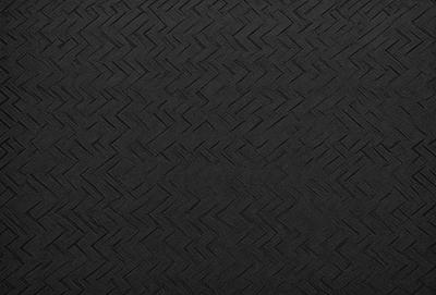 The primary subject of the image is a black and white patterned surface, which appears to be a textured wall or a black and white checkered pattern. The setting is a dark room, and the visual style is a close-up of the patterned surface. The colors and mood of the image are predominantly black and white, creating a sense of depth and contrast.