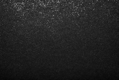 The primary subject of the image is a black background with a glossy, reflective surface. The setting is a dark room, and the visual style is a close-up of the black background. The colors and mood of the image are predominantly dark and moody, with the black background and glossy surface creating a sense of depth and intrigue.