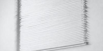 The primary subject of the image is a long, white, and thin strip of material, possibly a ribbon or a string. The setting is a white background, which provides a clean and minimalistic appearance. The visual style is a close-up of the strip, showcasing its texture and details. The colors and mood of the image are predominantly white, giving it a clean and simple appearance.