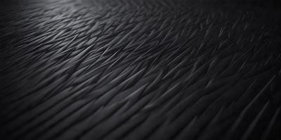 The primary subject of the image is a close-up of a black, textured surface. The setting appears to be a dark room, with the surface being the main focus of the image. The visual style is a close-up of a textured surface, which gives the image a somewhat moody and mysterious atmosphere.