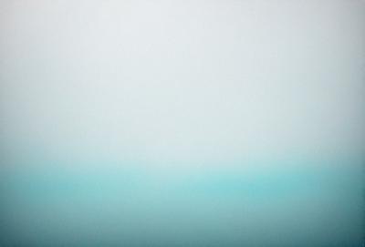 The primary subject of the image is a large body of water, which appears to be a vast ocean. The setting is a cloudy sky, creating a somewhat moody atmosphere. The visual style of the image is a photo, capturing the beauty of the ocean and the sky. The dominant colors in the image are blue and gray, reflecting the ocean and the sky.