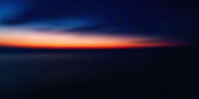 The primary subject of the image is the sunset, with the sun setting over the ocean. The setting is a vast expanse of water, with the sun's rays reflecting off the surface. The visual style is a photo, capturing the beauty of the sunset and the serene ocean landscape. The colors and mood of the image are warm and tranquil, with the sun's hues creating a picturesque scene.