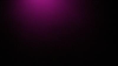 The primary subject of the image is a purple wall. The setting is a dark room, and the visual style appears to be a photo. The dominant colors are purple and black, creating a moody atmosphere.