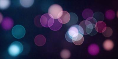 The primary subject of the image is a close-up of a brightly lit, colorful, and blurry background. The setting appears to be a dark room with a bright light source, creating a visually striking and artistic effect. The visual style of the image is a combination of a photo and digital art, as it captures the vibrant colors and blurred shapes of the background. The colors and mood of the image are predominantly bright and lively, with the blurred shapes and lights creating