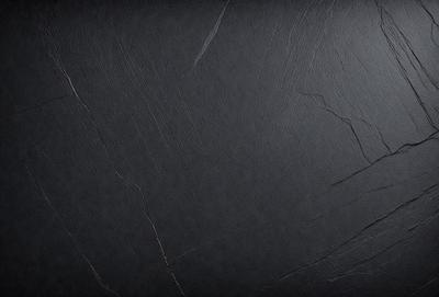 The primary subject of the image is a black surface, which appears to be a wall or a piece of artwork. The setting is a dark room, and the visual style is a close-up of the black surface. The colors and mood of the image are predominantly dark and moody, with the black surface being the main focus.